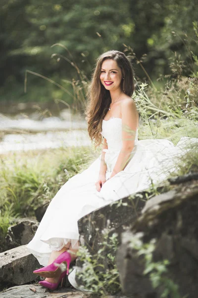 Ritratto di splendida sposa con lunghi capelli in piedi vicino al fiume — Foto Stock