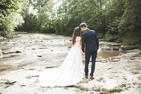 Elegante zachte stijlvolle bruid en bruidegom in de buurt van rivier met stenen. Bruidspaar in liefde — Stockfoto