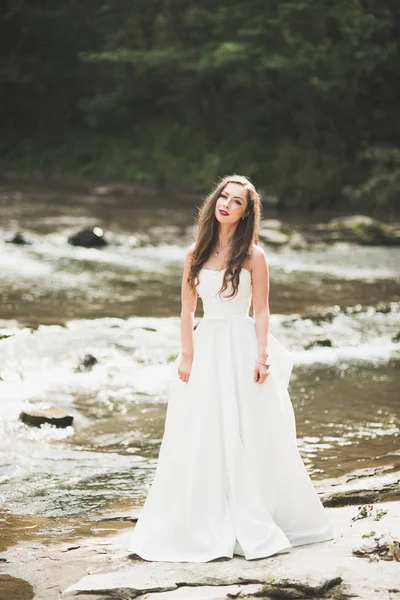 Porträt einer atemberaubenden Braut mit langen Haaren, die am Fluss steht — Stockfoto