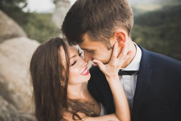 Happy wedding couple kissing and hugging near a high cliff — Stock Photo, Image