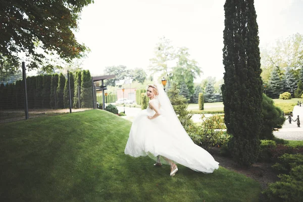 美しい花嫁でエレガントな白いドレス保持花束ポージングで公園 — ストック写真