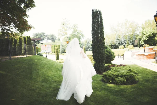 Όμορφη νύφη σε κομψό λευκό φόρεμα κρατώντας μπουκέτο ποζάρουν στο πάρκο — Φωτογραφία Αρχείου