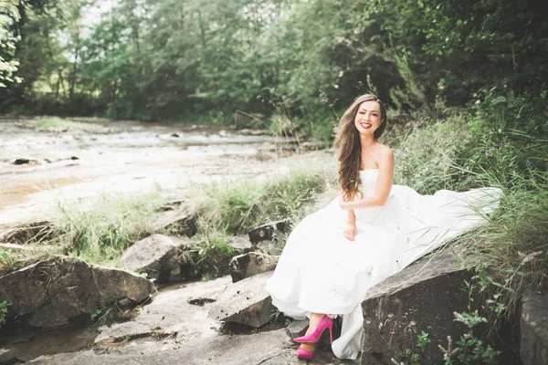 Porträt einer atemberaubenden Braut mit langen Haaren, die am Fluss steht — Stockfoto