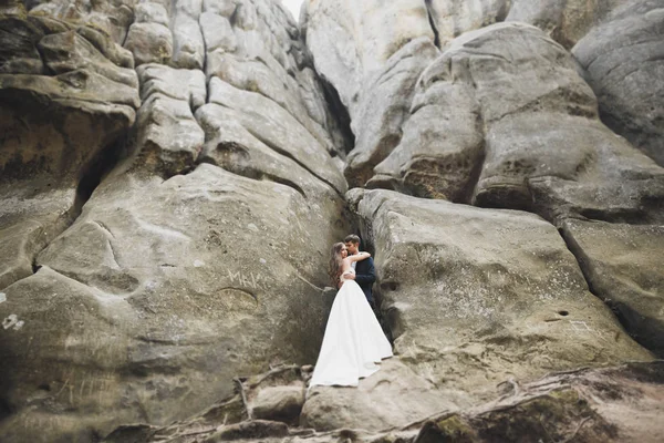 Boda pareja enamorada besándose y abrazándose cerca de rocas en hermoso paisaje —  Fotos de Stock