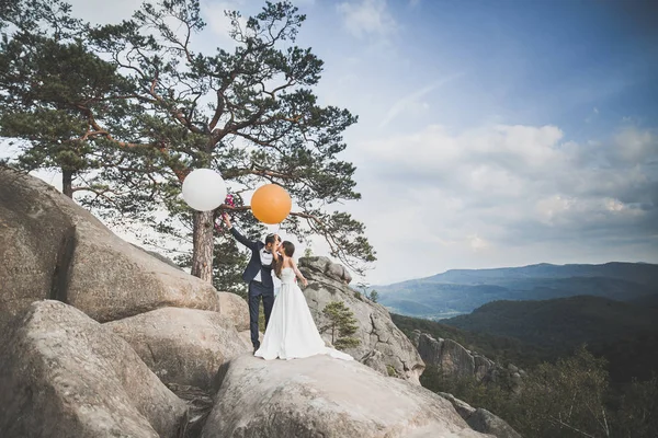 Poseren op een achtergrond van rock klif mooi gelukkig jong bruidspaar — Stockfoto