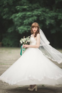 Çekici gelinin portresi, uzun saçlı, büyük buketli poz veren.