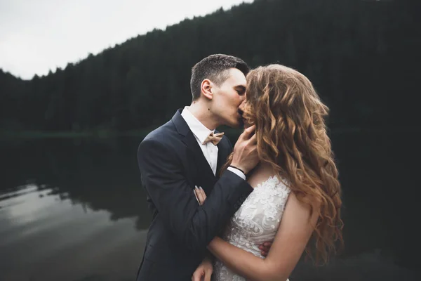 Όμορφη πανέμορφη νύφη ποζάρει στον γαμπρό και διασκεδάζει, πολυτελή τελετή στα βουνά με καταπληκτική θέα, χώρος για κείμενο, γαμήλιο ζευγάρι — Φωτογραφία Αρχείου