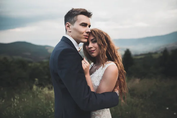 Hermosa pareja de boda besándose y abrazándose cerca de la montaña con vista perfecta —  Fotos de Stock