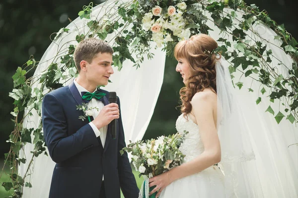 Romántico, cuento de hadas, feliz pareja recién casada abrazándose y besándose en un parque, árboles en el fondo — Foto de Stock