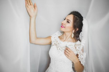 Cüppeli muhteşem gelin bir odada düğün töreni için poz veriyor ve hazırlanıyor.