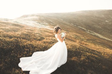 Gün batımında dağ zemin üzerine bir buket ile güzel gelin