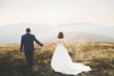 Bir dağın tepesinde günbatımında poz güzel düğün çifti