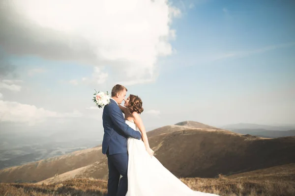 Hermosa pareja de boda besándose y abrazándose cerca de la montaña con vista perfecta —  Fotos de Stock
