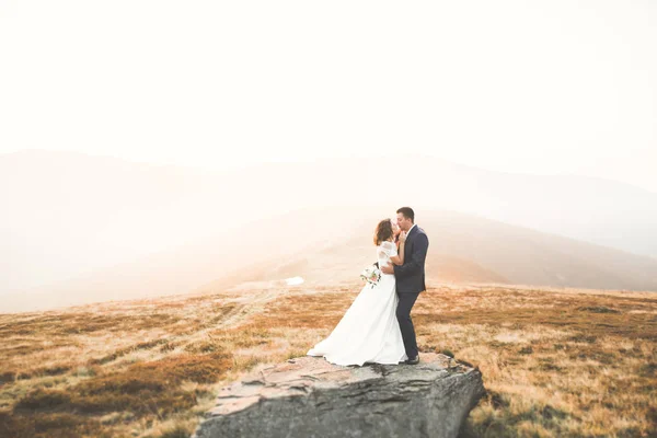 Jovem casal recém-casado, noiva e noivo beijando, abraçando na visão perfeita das montanhas, céu azul — Fotografia de Stock