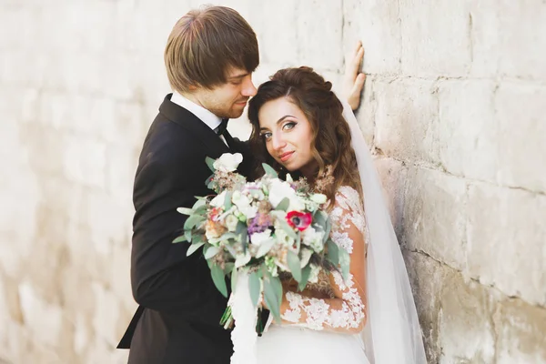 Stilvolles Brautpaar spaziert am Hochzeitstag mit Blumenstrauß durch den Park — Stockfoto