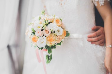 Gelin çiçekli büyük ve güzel bir düğün buketi tutuyor.