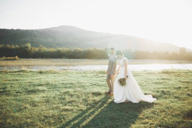 Muhteşem gelin ve şık damat yürüyüş güneşli manzara, Düğün çifti, lüks töreni dağların muhteşem manzaralı, metin için yer