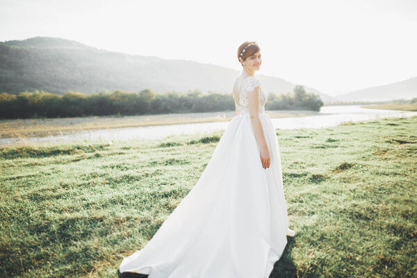 Beauty woman, bride with perfect white dress posing on the rock background mountains.