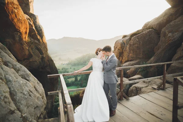 Jovem casal recém-casado, noiva e noivo beijando, abraçando na visão perfeita das montanhas, céu azul — Fotografia de Stock