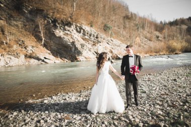 Düğün çifti, damat ve gelin kucaklaşıyor, nehir kenarında.