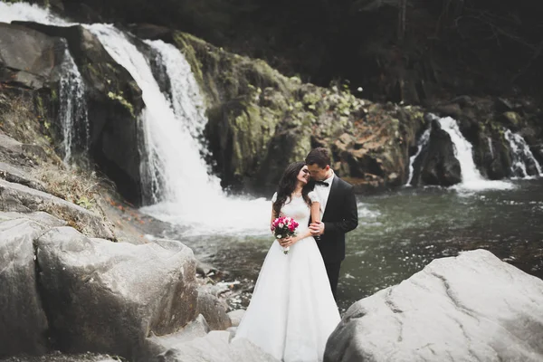 Boda pareja enamorada besándose y abrazándose cerca de rocas en hermoso paisaje —  Fotos de Stock