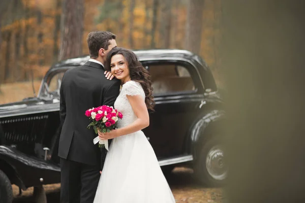 Piękny ślub para pozowanie w pobliżu wspaniały samochód retro — Zdjęcie stockowe