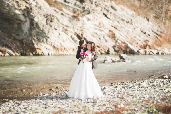 Svatební pár, ženich a nevěsta objímání, venku u řeky — Stock fotografie