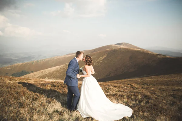 Schönes Hochzeitspaar posiert bei Sonnenuntergang auf einem Berg — Stockfoto