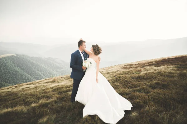 Hermosa pareja de boda besándose y abrazándose cerca de la montaña con vista perfecta —  Fotos de Stock