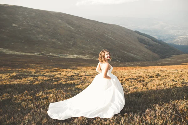 Belle mariée avec un bouquet sur fond de montagne au coucher du soleil — Photo