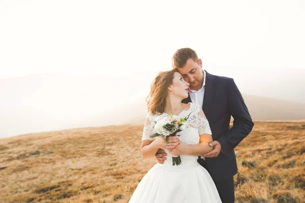 Joyeux beau couple de mariage mariée et marié le jour du mariage à l'extérieur sur le rocher des montagnes. Couple mariage heureux en plein air sur la nature, douces lumières ensoleillées — Photo