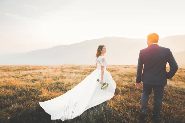 Красива весільна пара позує на вершині гори на заході сонця — стокове фото