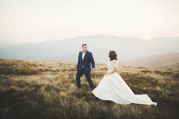 Bruidspaar poseren op zonsondergang op de trouwdag. Bruid en bruidegom verliefd — Stockfoto