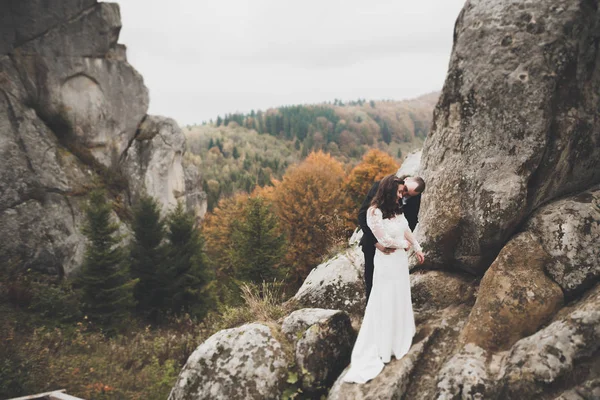 Wedding couple in love kissing and hugging near rocks on beautiful landscape — Stock Photo, Image