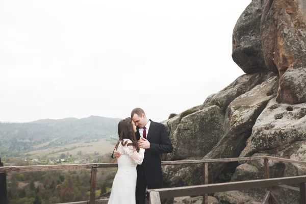 Wedding couple in love kissing and hugging near rocks on beautiful landscape — Stock Photo, Image