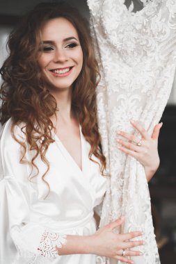 Cüppeli muhteşem gelin bir odada düğün töreni için poz veriyor ve hazırlanıyor.