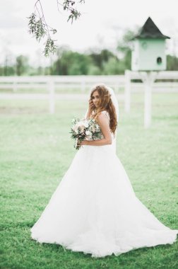 Çekici gelinin portresi, uzun saçlı, büyük buketli poz veren.