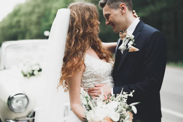 Stilvolles Hochzeitspaar, Braut, Bräutigam küssen und umarmen sich im Retro-Auto — Stockfoto