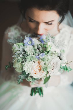 Cüppeli muhteşem gelin bir odada düğün töreni için poz veriyor ve hazırlanıyor.