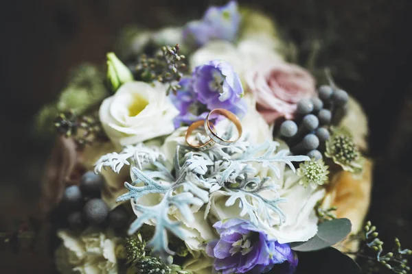 Gyönyörű tónusú kép jegygyűrűkkel a háttérben egy csokor virág — Stock Fotó