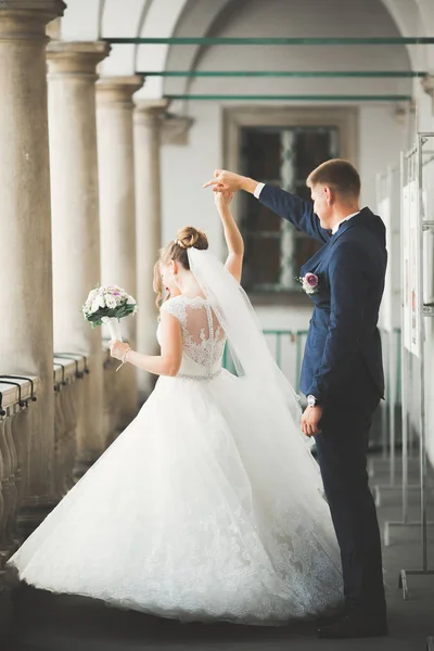 Прекрасна щаслива весільна пара, наречена з довгим білим платтям позує в красивому місті — стокове фото