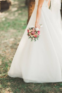 Gelin çiçekli büyük ve güzel bir düğün buketi tutuyor.