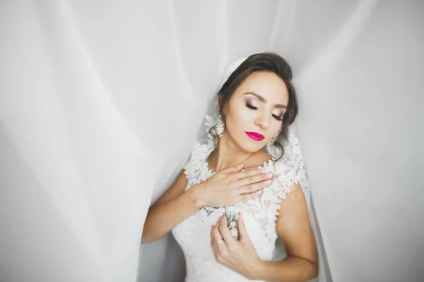 Preciosa novia en bata posando y preparándose para la ceremonia de boda cara en una habitación — Foto de Stock