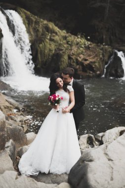 Düğün çifti, damat ve gelin kucaklaşıyor, nehir kenarında.