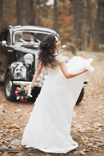 Piękna panna młoda w eleganckiej białej sukience gospodarstwa bukiet pozowanie w parku — Zdjęcie stockowe