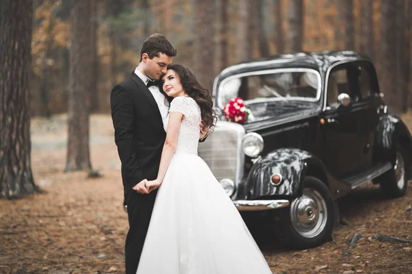 Elegante pareja de boda, novia, novio besándose y abrazándose cerca de coche retro en otoño —  Fotos de Stock