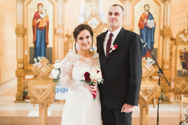 Casal casal posando em uma igreja após a cerimônia — Fotografia de Stock