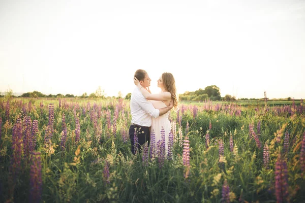 彼は夕日の光線で彼女をキスをしながら、花嫁は新郎の首を保持しています。 — ストック写真