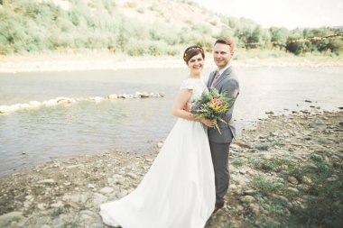 Zarif nazik şık damat ve gelin taşlarla Nehri yakınında. Evlilik çift aşık