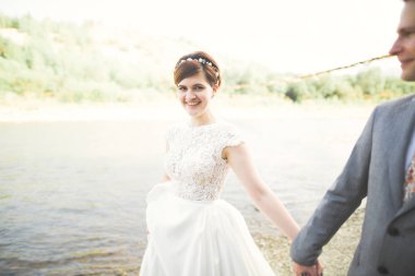 Gelin ve damat güzel düğün buket tutarak. Nehir kenarında poz